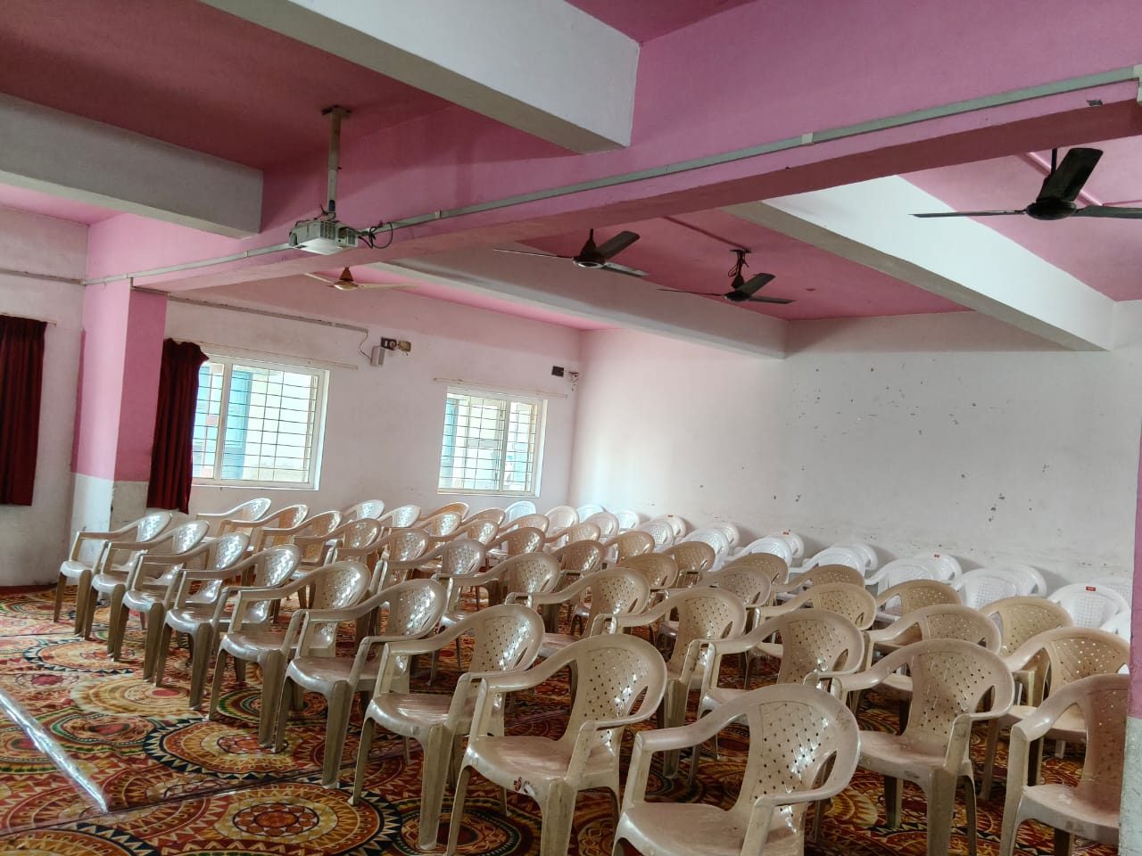 Wide view of the seminar hall with projector and ceiling fans